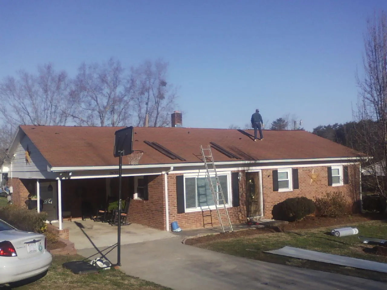 Roofer stripping a shingle roof on a brick ranch before metal panels in Torrance