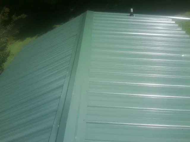 New green metal panels meeting at the ridge of a roof — Flat Roof Repair work by our crew in Torrance