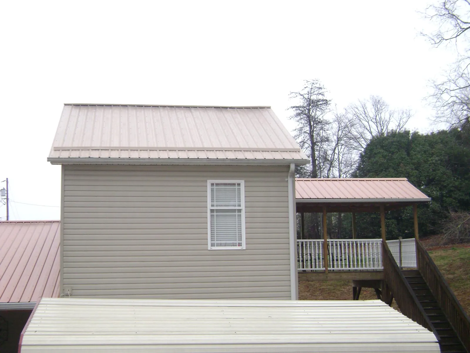 Tan metal roofs on a two story addition and attached porch, from a Roof Replacement job in Torrance
