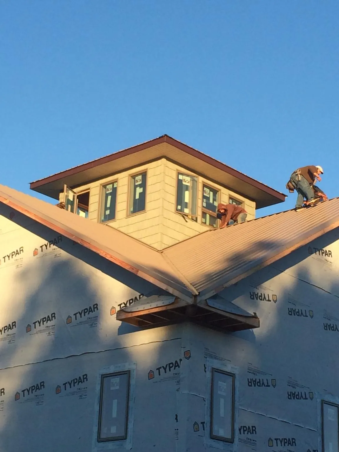 Roofers working around a rooftop cupola on a new metal roof at sunset — Roof Waterproofing in Torrance by Roofing Brothers